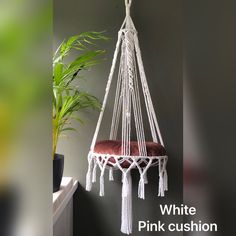 a white hammock hanging from the ceiling next to a potted plant