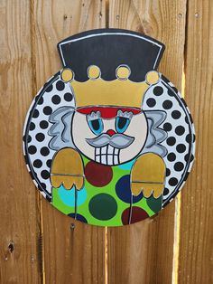 a colorful clown painted on the side of a wooden fence