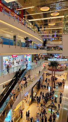 an indoor mall with people walking around and on the escalators in front of them