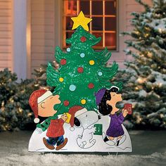 a charlie brown christmas tree with peanuts around it in front of a house and trees