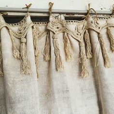 curtains with tassels hanging from them in front of a white window sill