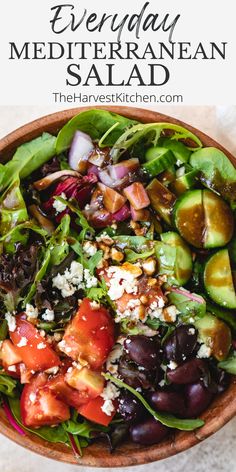 a salad with tomatoes, cucumber, olives and feta cheese in a wooden bowl