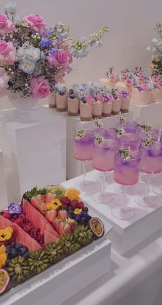 there are many different types of drinks on the table with flowers and vases behind them