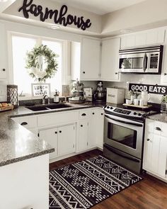 a kitchen with white cabinets, black and white rugs and an area rug on the floor