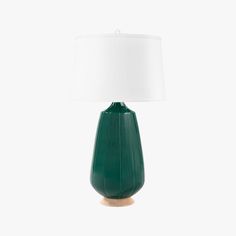 a green table lamp with a white shade on the base and a wooden base, in front of a white background