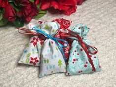 three small bags with red flowers in the background