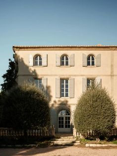 an old building with many windows and shutters on the front, surrounded by trees