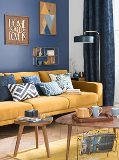 a living room with blue walls and yellow furniture in the center, along with coffee table