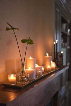 candles are arranged on a shelf with a flower in a vase