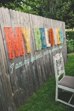 a chair sitting in front of a wooden fence with the word marry painted on it