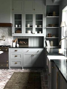 a kitchen with gray cabinets and marble counter tops, along with an area rug on the floor