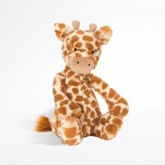 a stuffed giraffe sitting on the ground with it's legs spread out