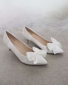 a pair of white shoes with bows on them