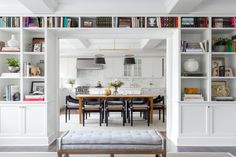 an open kitchen and dining room area with built in bookshelves on the wall