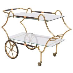 a glass and brass serving cart with wheels