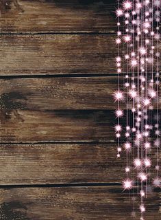 a wooden background with pink and white lights hanging from it's sides, on top of wood planks