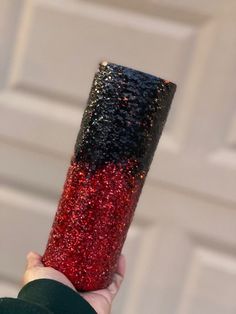 a hand holding a red and black glittered cup