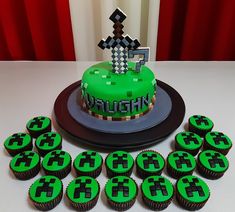 cupcakes with green frosting and black icing are next to a cake