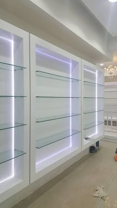 an empty room with shelves and lights on the wall