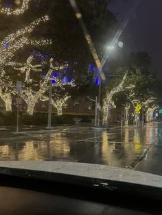 the street is covered with christmas lights and trees on both sides of the road at night