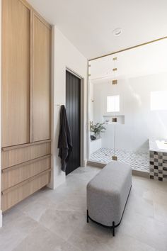 a white bathroom with a bench, shower and cabinets in the back ground floor area