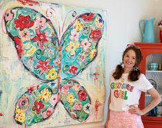 a woman standing in front of a butterfly painting