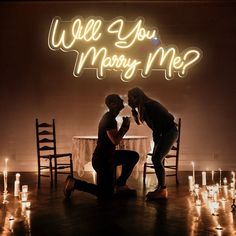 two people sitting at a table in front of candles with the words, will you marry me?