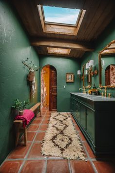 a bathroom with green walls and tile flooring has a skylight above the sink