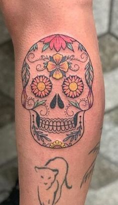 a woman's leg with a skull and flowers tattoo on the side of her leg