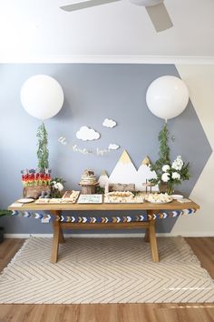 a table with desserts and balloons on it in front of a wall painted blue