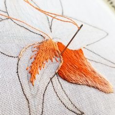 an orange leaf is stitched on to a piece of fabric