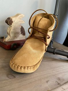 a pair of brown suede shoes sitting on top of a wooden table next to a figurine