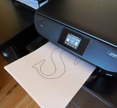 a printer with the letter s on it is sitting on top of a table next to a piece of paper