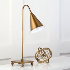 a table lamp sitting on top of a white counter next to a vase and bowl