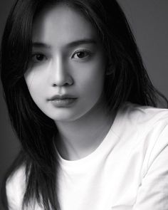 black and white photograph of a woman with long hair wearing a t - shirt looking at the camera