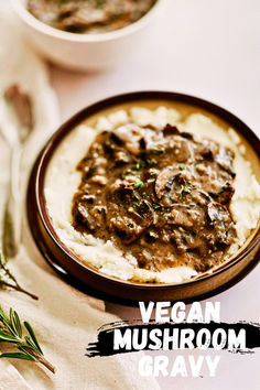 a bowl filled with mashed potatoes covered in mushroom gravy next to a spoon