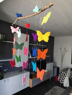 colorful paper butterflies hanging from a tree branch in a living room or dining room area