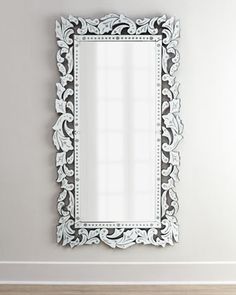 a white mirror sitting on top of a wooden floor next to a wall mounted shelf