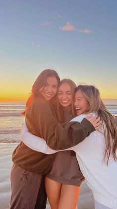 three girls hugging on the beach at sunset