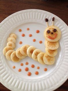 a white plate topped with pancakes and a caterpillar made out of banana slices