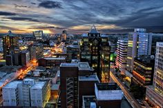 the city is lit up at night with lights on and buildings in the foreground