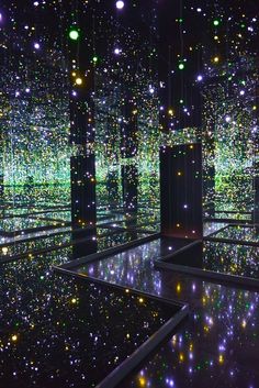 a room filled with lots of shiny lights and black floored floors covered in green and yellow balls