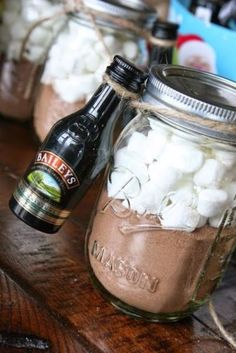 two mason jars filled with marshmallows on top of a wooden table next to a beer bottle