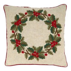 a christmas wreath pillow with holly and red berries on the front, sitting on a white background