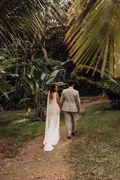 a bride and groom walking through the jungle