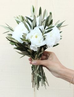 a hand holding a bouquet of white flowers