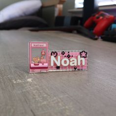 a pink and white plastic name tag sitting on top of a wooden table next to a video game controller