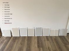 white paint samples lined up on the floor in front of a wall with information about them