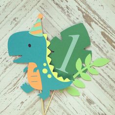 a dinosaur cake topper with the number one on it