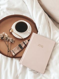 a cup of coffee and a book on a bed